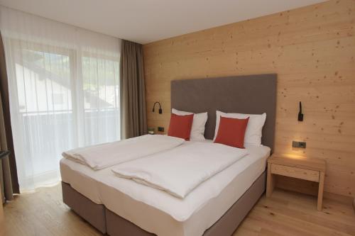 卢塔戈Appartments Hopfgartner Eurospar的卧室配有带红色枕头的大型白色床