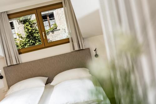 卡尔达罗Apartments Seewinkel的卧室配有带白色枕头的床和窗户。