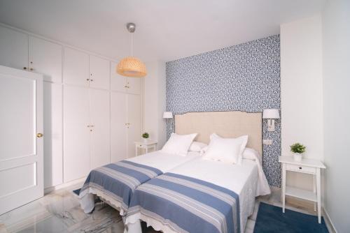 塞维利亚Arco Macarena Suite的一间卧室配有一张带蓝白条纹毯子的床