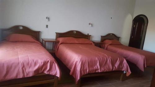 圣克鲁斯Hotel el super 8的宿舍间的三张床,配有红色床单