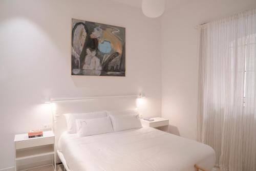 吉塔里亚NUEVO Katu Kale Apartamentuak CENTRO HISTORICO的卧室配有白色的床和墙上的绘画作品