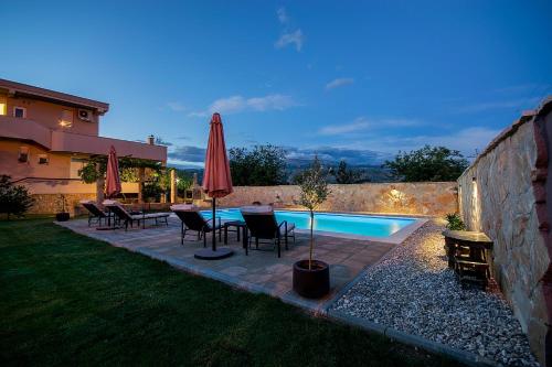 莫斯塔尔Villa Dama的后院设有游泳池、桌子和遮阳伞