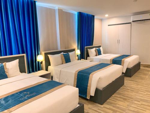 芹苴LION HOTEL的两张位于酒店客房的床,配有蓝色窗帘