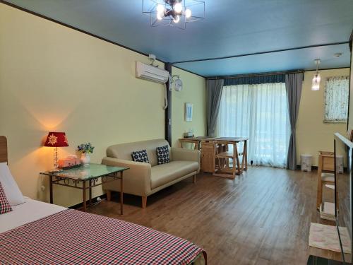 加平魅力旅馆的客房设有床、沙发和桌子。