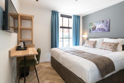埃丹Hof van Holland Hotel的一间卧室配有一张床、一张书桌和一个窗户。
