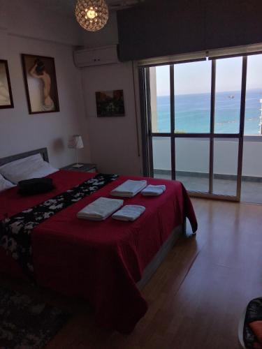 利马索尔Amazing Sea Place的一间卧室配有一张带红色床单的床和大窗户。