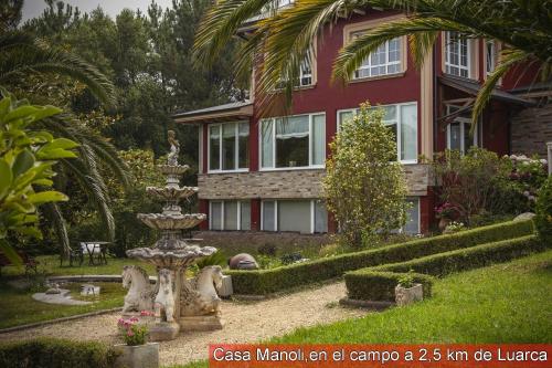 AlmuñaCasa Manoli Luarca的房屋前有喷泉的房屋