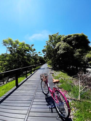 台东爱旅民宿 的木板路上的粉红色自行车