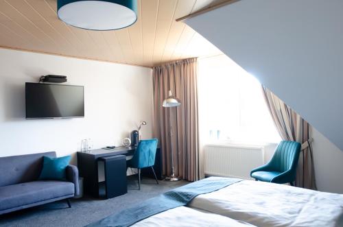 Sassenberg埃姆菲尔德马科斯旅馆的酒店客房设有一张床、一张书桌和一台电视机。