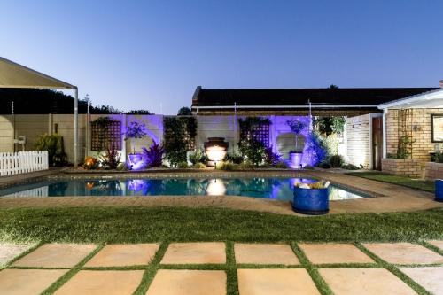 伊丽莎白港Wagtails Guest House的后院游泳池晚上配有紫色灯