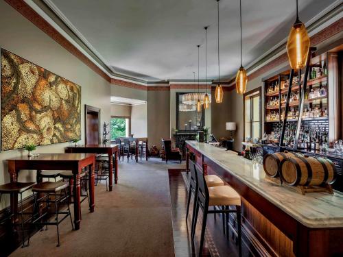 阿德莱德Mount Lofty House & Estate Adelaide Hills的餐厅设有酒吧,配有桌椅