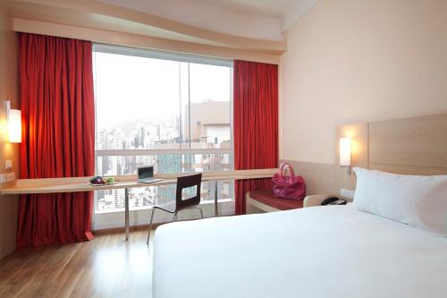 香港宜必思香港中上環的配有一张床、一张书桌和一扇窗户的酒店客房