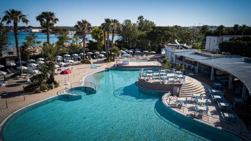 圣伊西多罗萨兰托村蓝色酒店的享有带椅子和遮阳伞的游泳池的上方景色