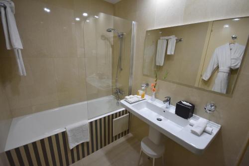 迦玛特Ramada Plaza by Wyndham Tunis的浴室配有水槽、淋浴和浴缸。