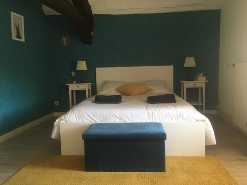 ArandasAuberge à la Vieille Cure的一间卧室配有一张带两张桌子的床和蓝色的搁脚凳