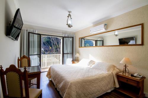 坎波斯杜若尔当内华达酒店的一间卧室配有一张床、镜子和电视