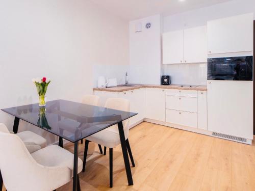 科沃布热格Apart111 Apartamenty - Garden的厨房配有黑桌和白色椅子