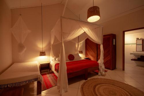 马劳Na Villa dos Algodões的一间卧室配有天蓬床和红色地毯。