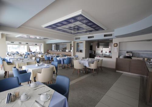 哈尔基斯费洛泽尼亚酒店的餐厅设有白色的桌子和蓝色的椅子