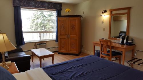 欣顿松林汽车旅馆的一间卧室配有一张床、一张书桌和一个窗户。