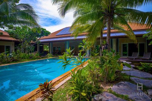 七岩6 Bedroom Luxury Villa on Golf Course PH125的棕榈树屋前的游泳池