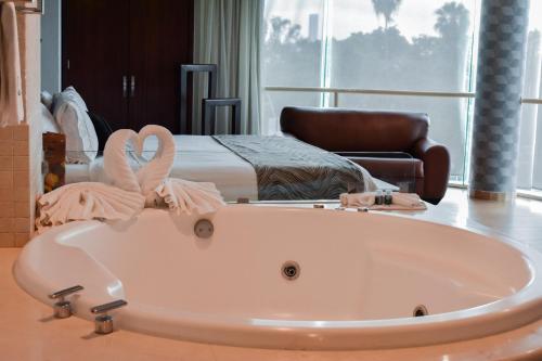 瓜达拉哈拉波托韦洛酒店的卧室前的浴缸,卧室配有一张床