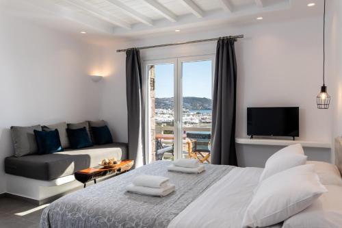 米克诺斯城Magic View Suites Mykonos的一间卧室配有一张床、一张沙发和一台电视。