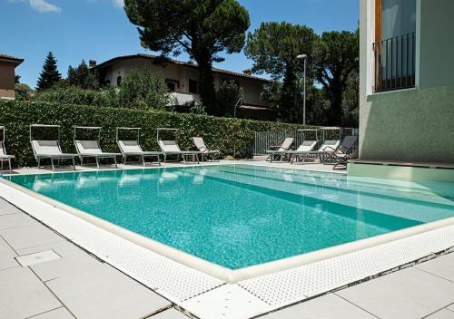 西尔米奥奈Sirmione Rosselli Apartments的一个带躺椅和椅子的游泳池
