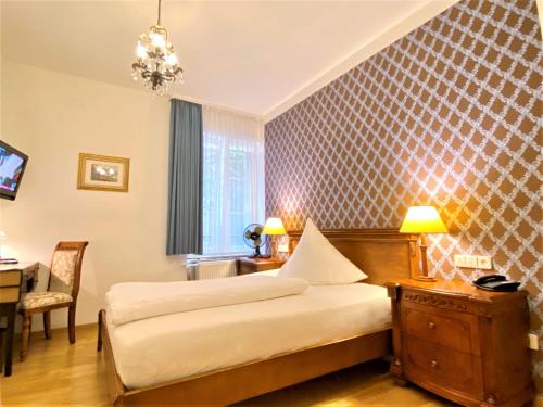 巴登-巴登雷达斯戈洛克酒店的酒店客房设有两张床、一张桌子和一张书桌。