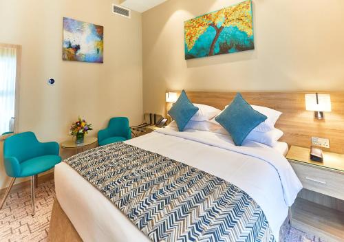 迪拜Rose Plaza Hotel Al Barsha的酒店客房,配有一张床和两张蓝色椅子