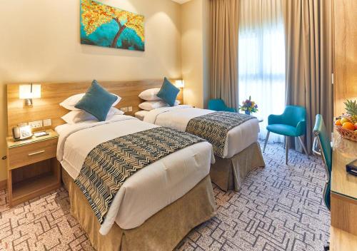 迪拜Rose Plaza Hotel Al Barsha的酒店客房配有两张床和一张书桌