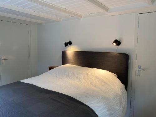 哈克斯卑尔根t Melkhuisje - EV lader aanwezig!的一间卧室配有白色床单和灯。
