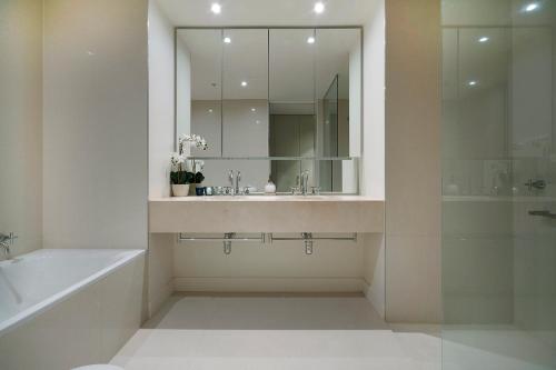 墨尔本Platinum Luxury Stays at Freshwater Place的一间带水槽、浴缸和镜子的浴室