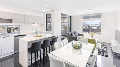 布里斯班Oaks Brisbane Woolloongabba Suites的厨房以及带白色桌椅的用餐室。