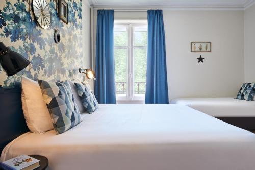 南希Hôtel Stanley by HappyCulture的一间卧室配有一张大床、蓝色窗帘和窗户