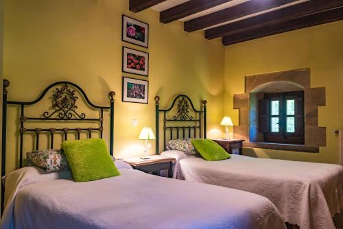 圭梅斯Posada Camino del Norte的一间卧室配有两张床,提供白色的床单和绿色的枕头