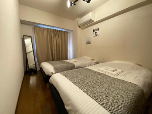 东京Residential Hotel Bevel Tokyo的酒店客房设有两张床和窗户。