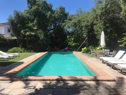 SotograndeLa Dulcinea的庭院内的游泳池配有椅子和遮阳伞