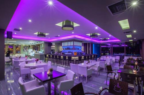 古厄庇道鲁斯STORK Design Suites的餐厅配有白色的桌椅和紫色的灯光