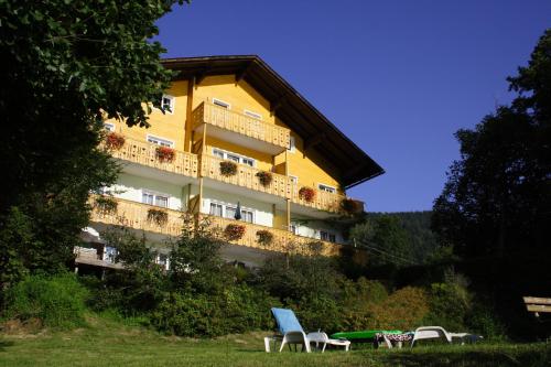 奥西阿赫Seehaus Karantanien am Ossiacher See的前面有椅子的黄色建筑