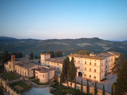 卡索莱德尔萨Castello di Casole, A Belmond Hotel, Tuscany的享有建筑的空中景观,以群山为背景