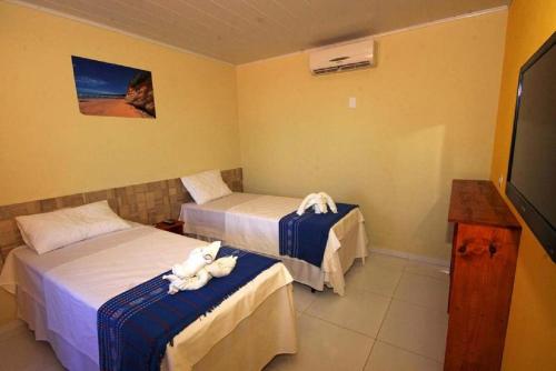 雅帕拉廷加Pousada Mama Pereira的酒店客房设有两张床和电视。