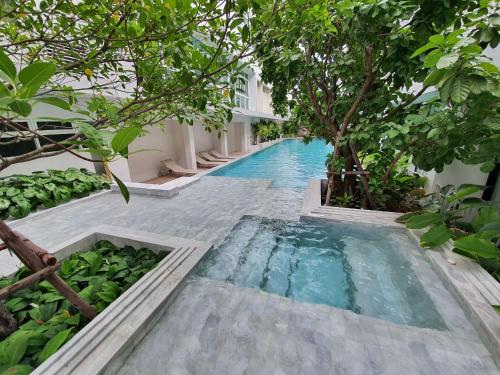 曼谷CHERN Bangkok的一座树木繁茂的建筑中间的游泳池