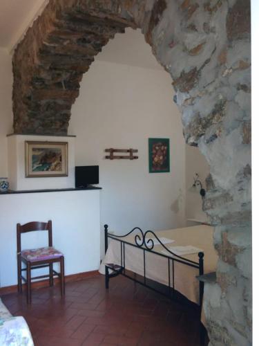 MontaleAppartamento Il Girasole的一间卧室设有石墙、一张床和一把椅子