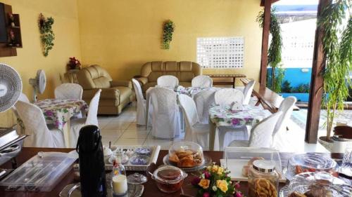 São Gonçalo do AmarantePousada e Posto Amigão的客厅配有白色椅子和餐桌,