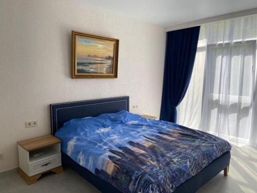 格里比夫卡Золотой Бугаз Грибовка的一间卧室配有一张带蓝色棉被的床和窗户。