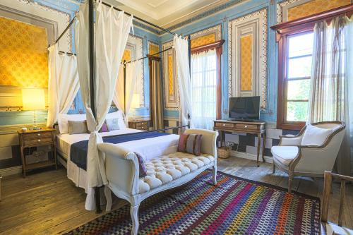 艾瓦勒克马卡龙科纳基旅馆的一间卧室配有一张天蓬床和一台电视机