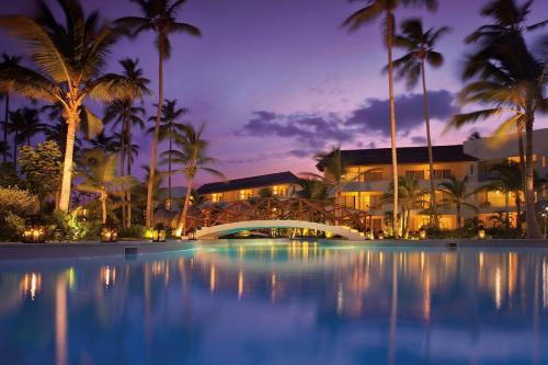 蓬塔卡纳Dreams Royal Beach Punta Cana - All Inclusive的夜间带游泳池和棕榈树的度假村