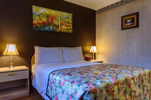 皇后区法拉盛中央酒店的一间卧室配有一张床和两个带灯的床头柜