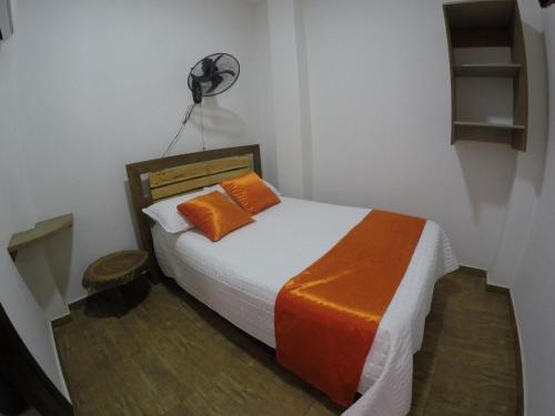 MangueHotel Campestre Maguey的一间卧室配有一张带橙色枕头的床和风扇